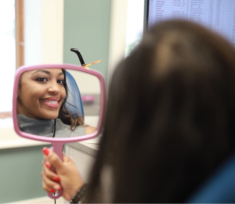 adult patient smiling and looking into mirror